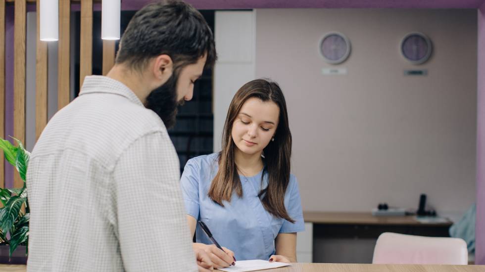 Patient signing documents at clinic reception desk during first visit