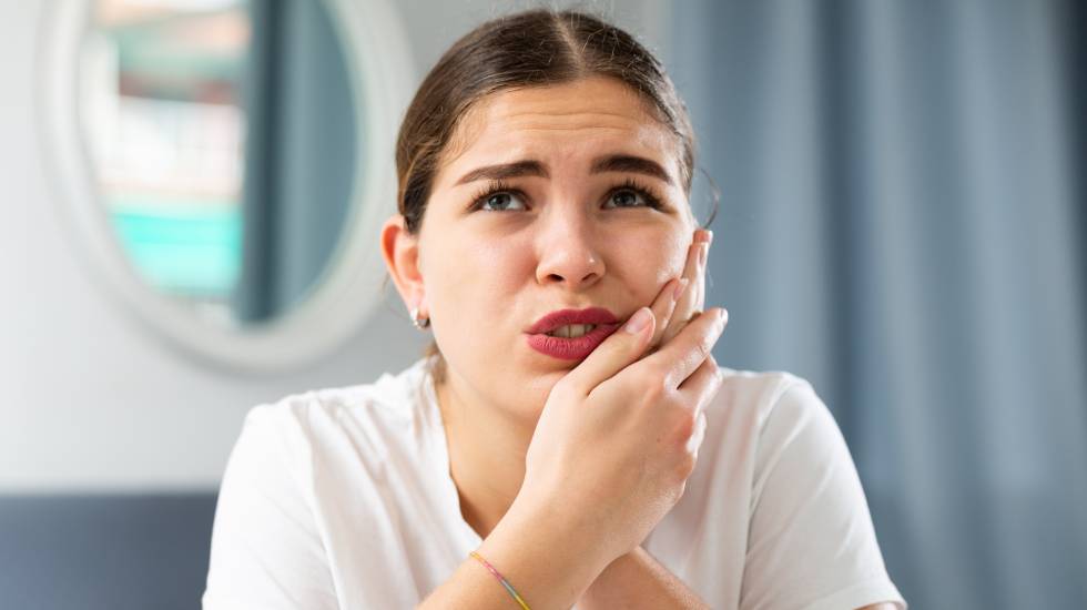 Young woman suffering from toothache touching her cheek